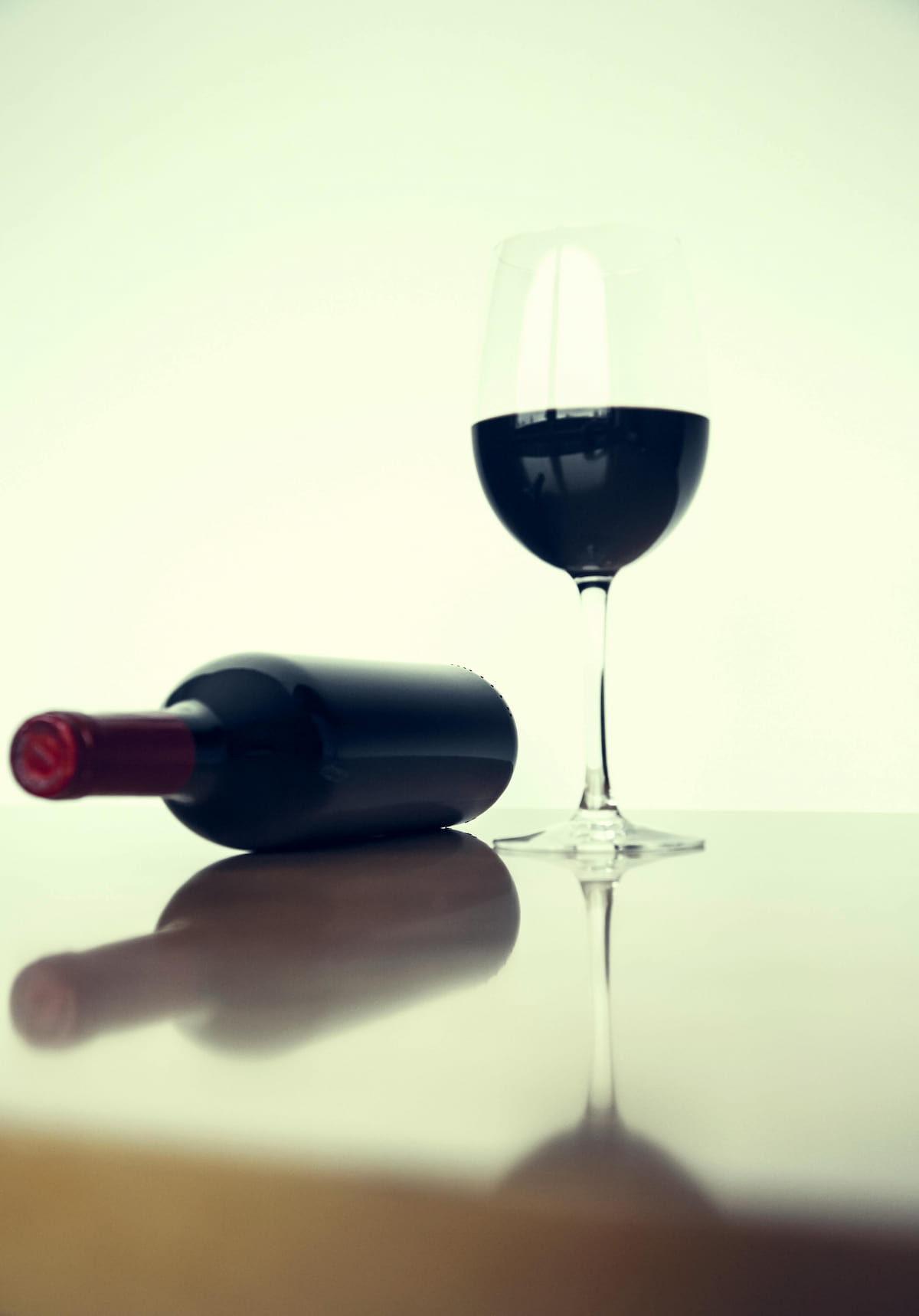 Red wine bottle and glass on a dark table